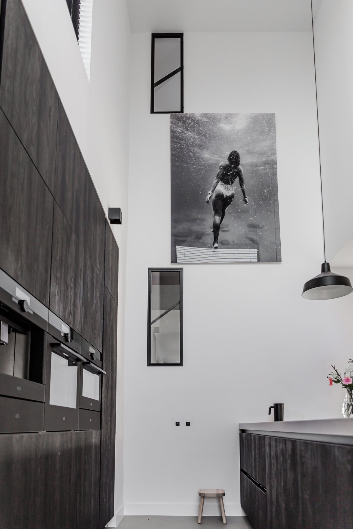 Donkere keuken met een stalen raamkozijn en zwart-witfoto aan de wand