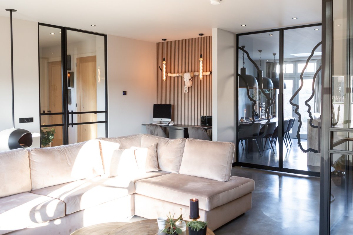 Woonkamer met lichte bank en glaswand met kunstwerk