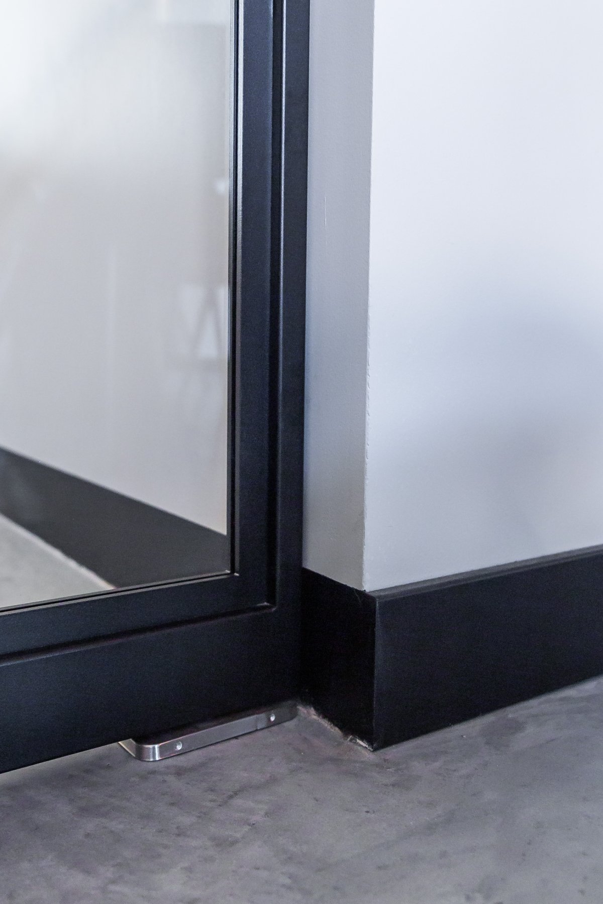 Hoekdetail van een zwarte stalen deur met glaslat