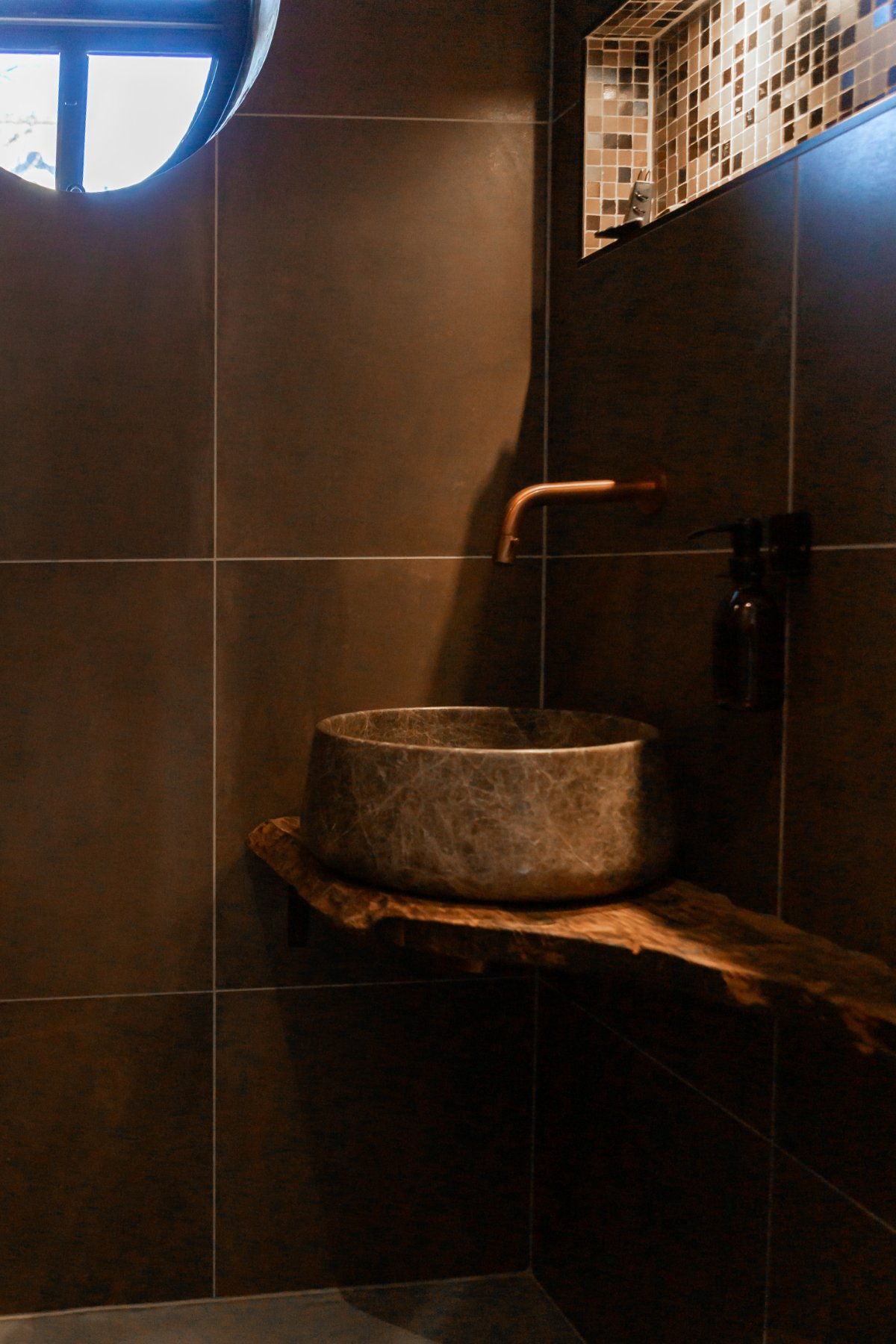 Badkamer met natuurstenen waskom en ronde patrijspoort