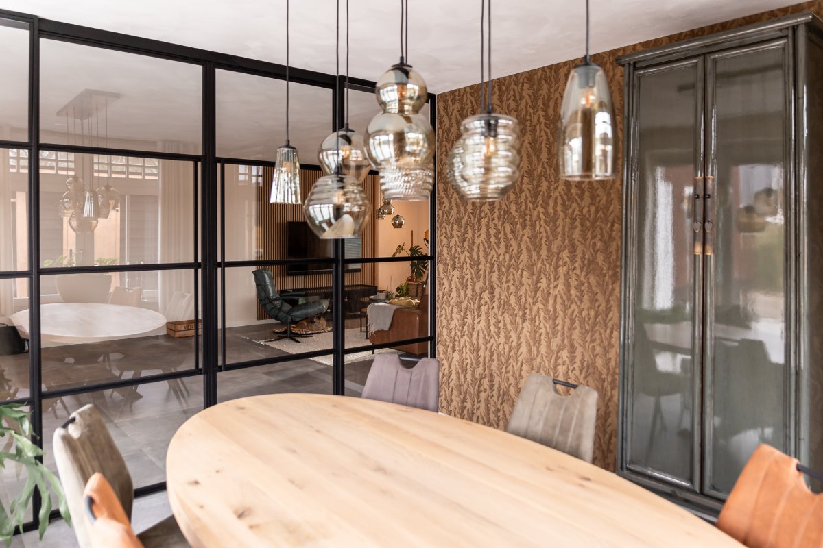 Glaswand met uitzicht op de eettafel en hanglampen